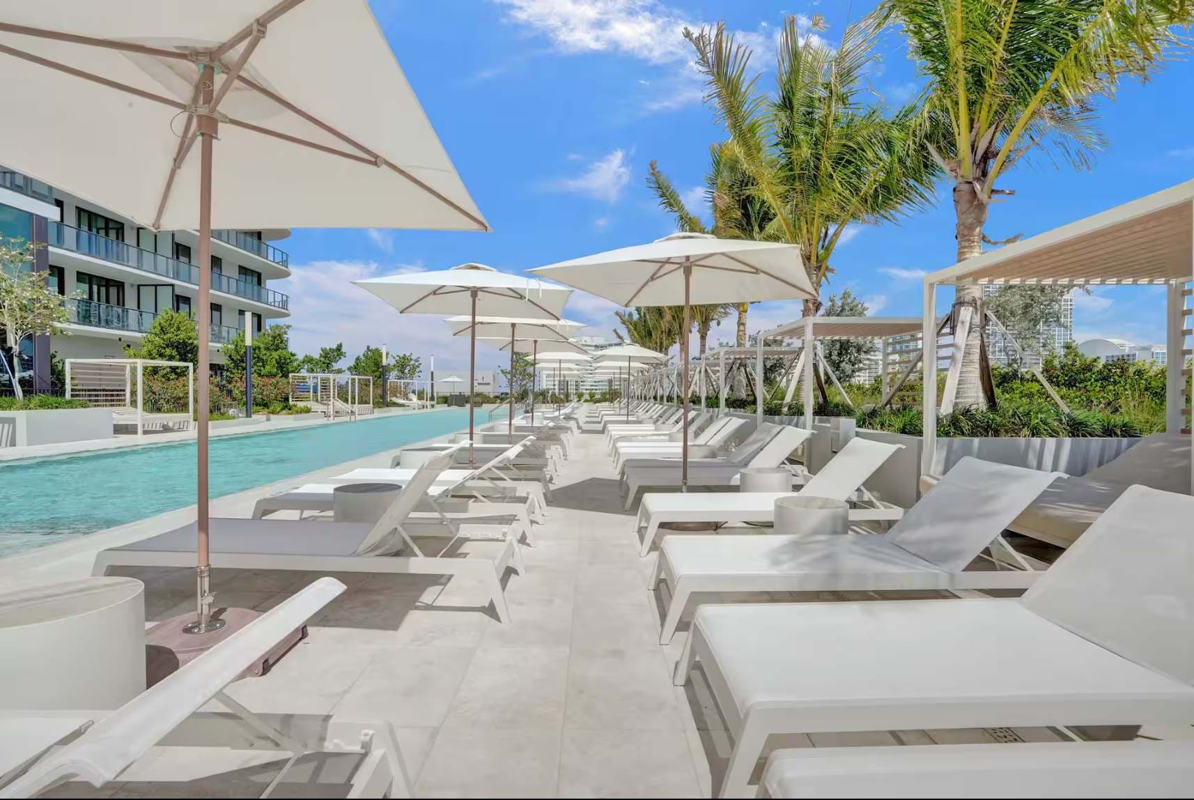 Poolside loungers beneath white umbrellas.