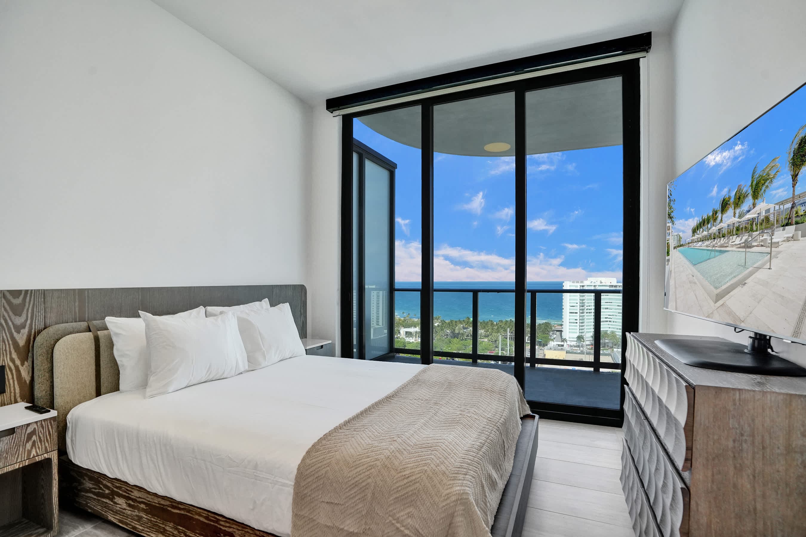 Bed beside balcony doors with ocean views.