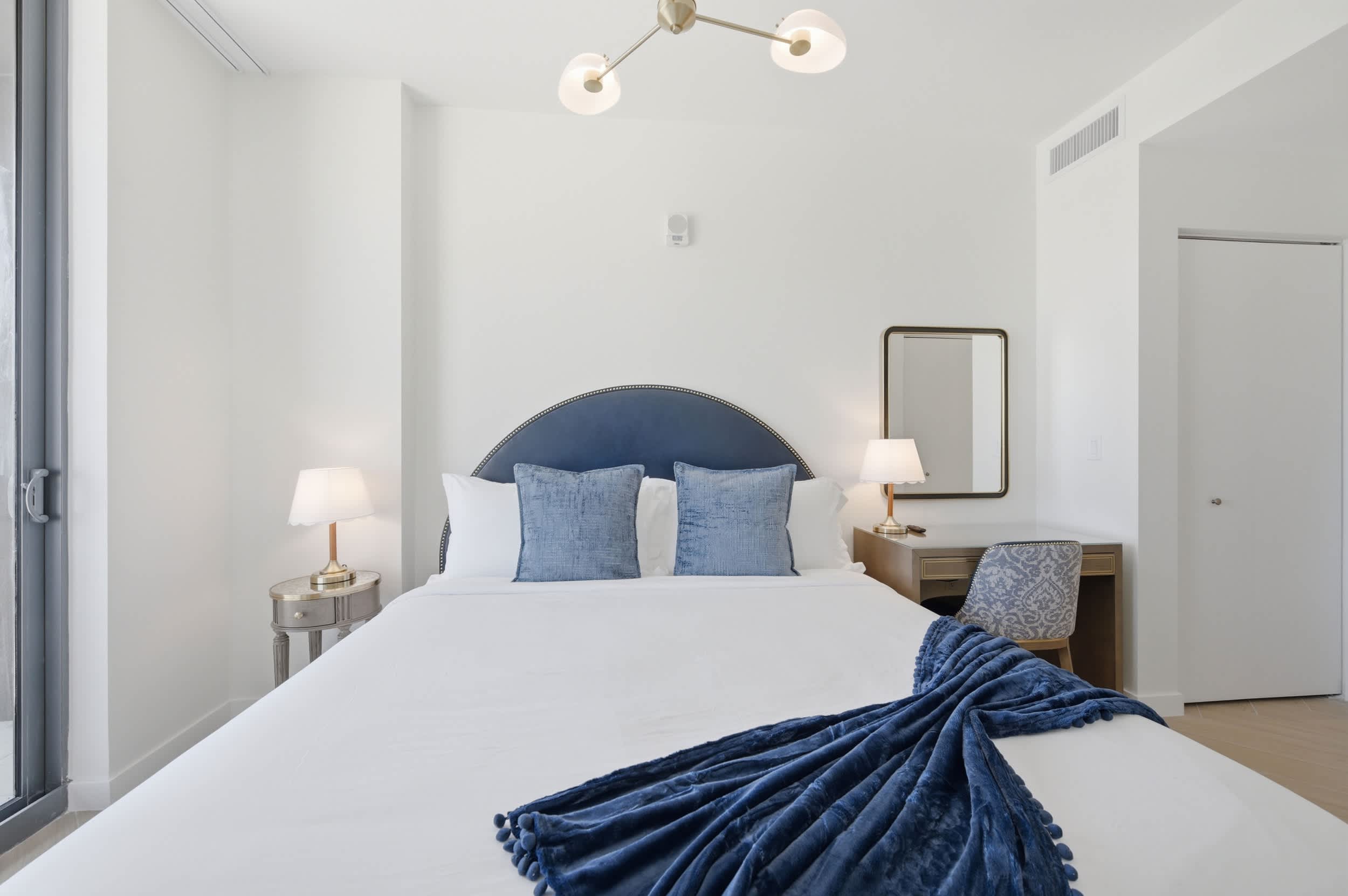 Bed with a blue headboard and matching throw.