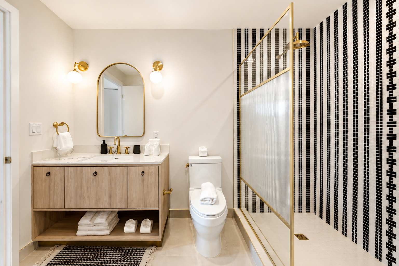 Bathroom with a wood vanity and striped shower tiles.
