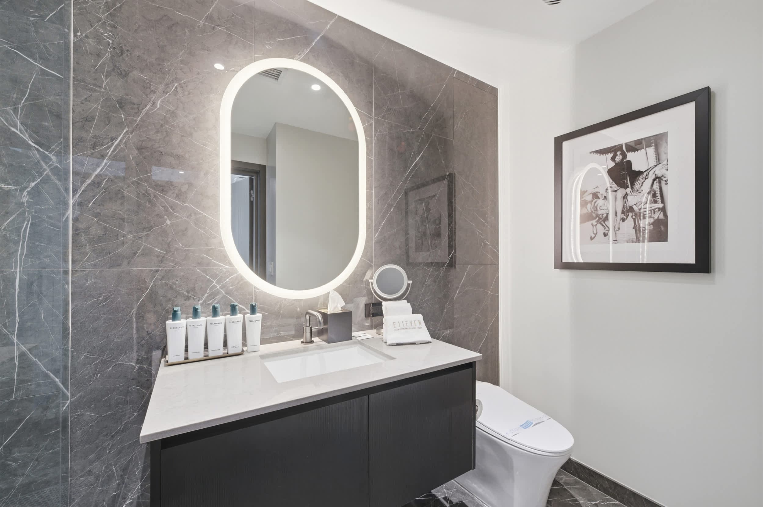 Bathroom vanity beneath an illuminated oval mirror.