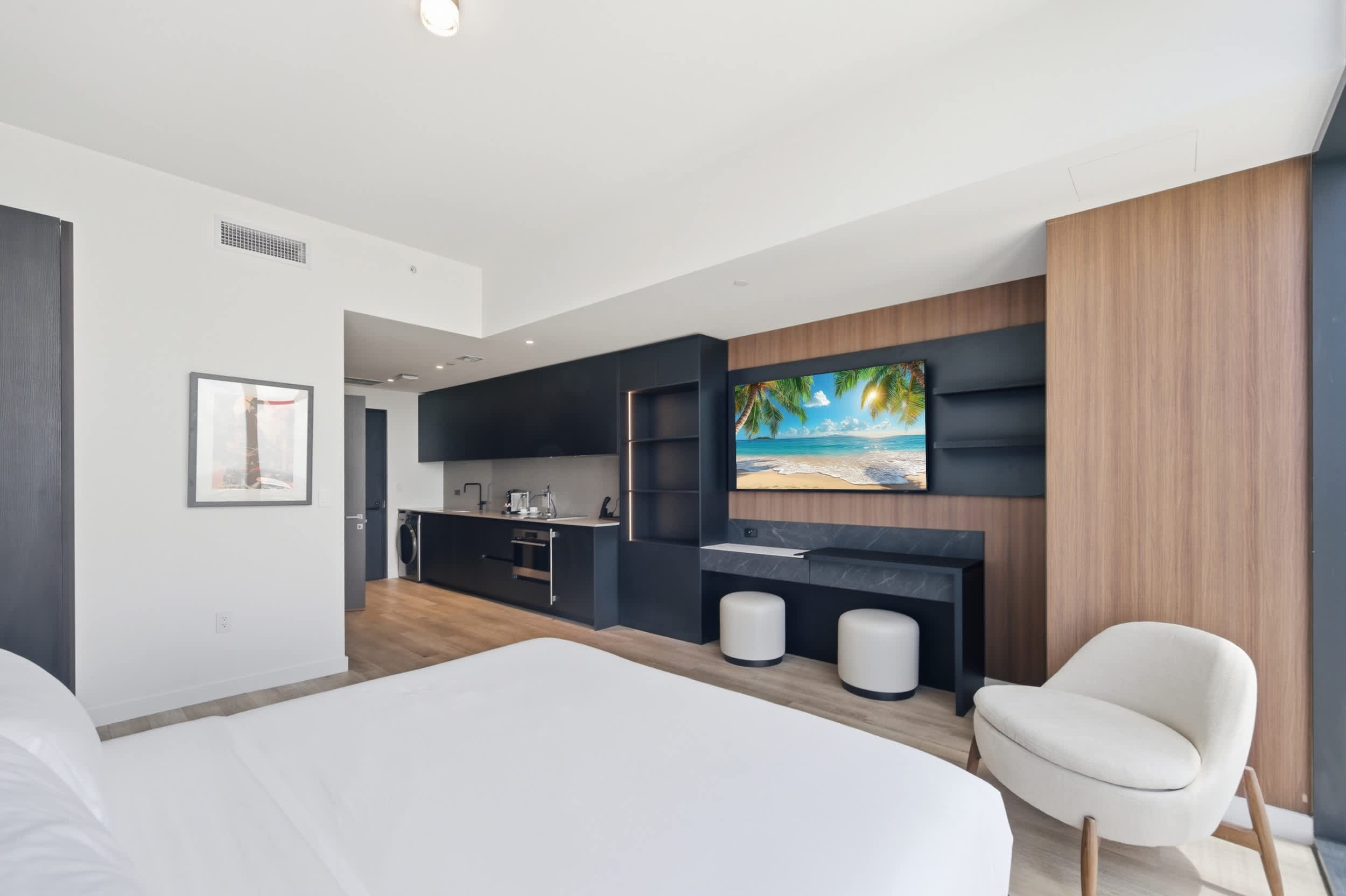 Bed facing a wall-mounted TV and long console.