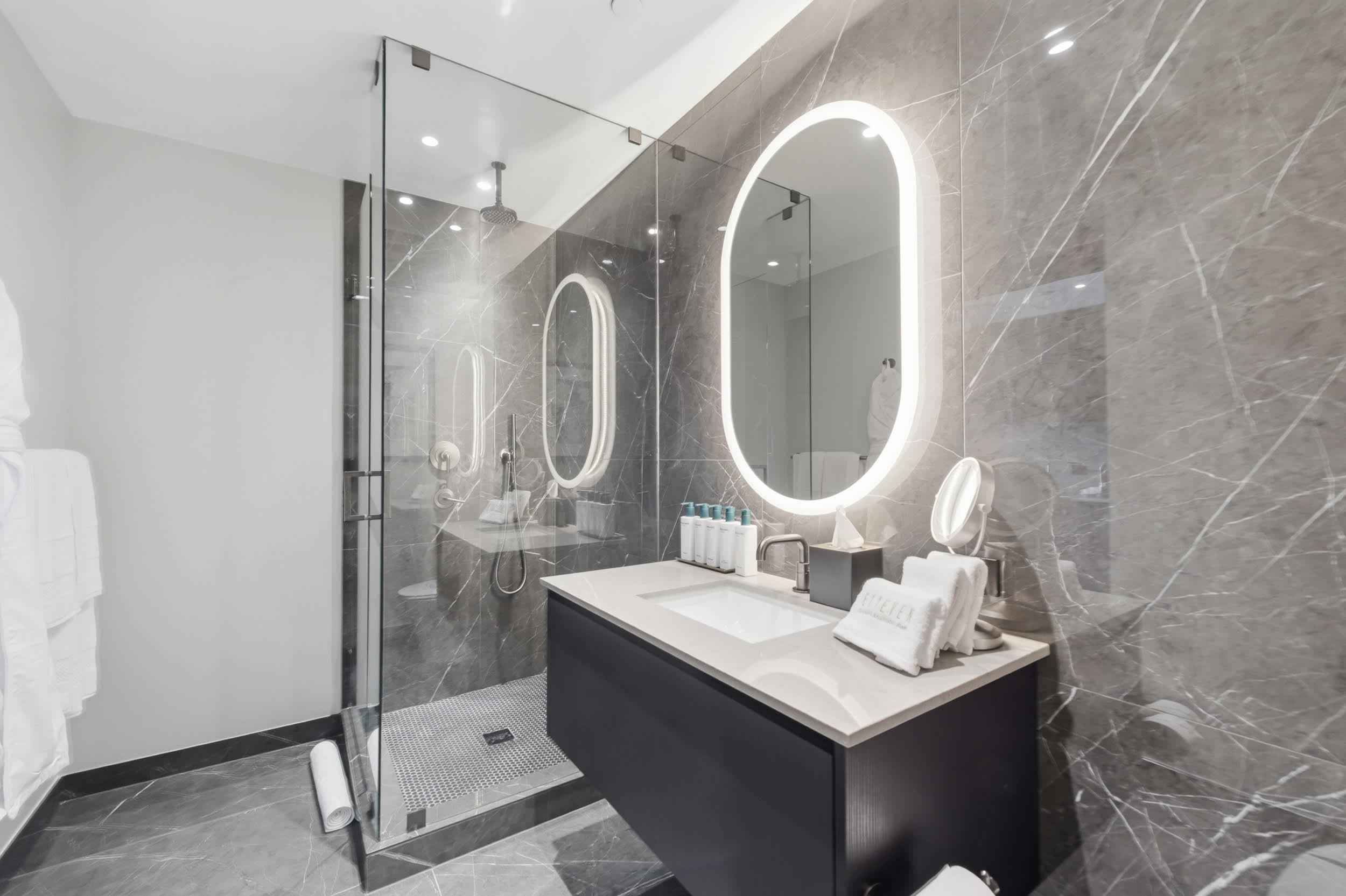 Marble bathroom with an oval mirror and shower.