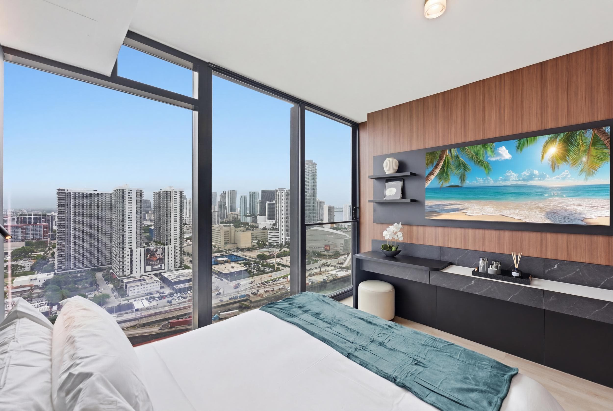 Bed beside floor-to-ceiling city-view windows.