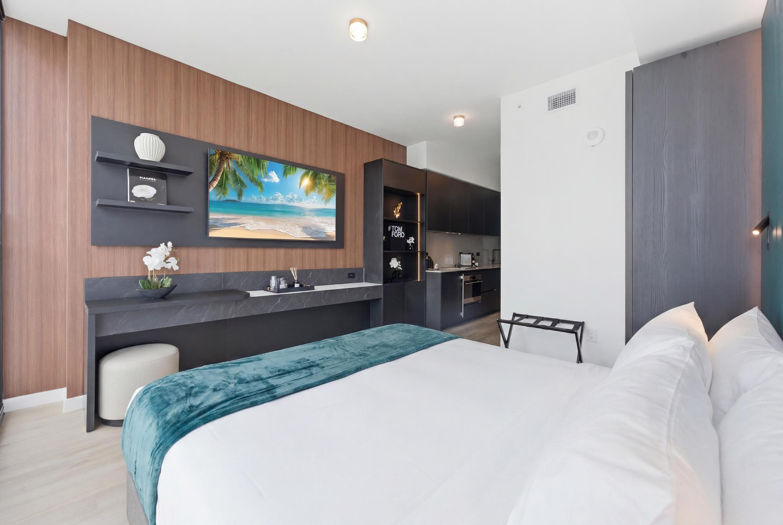 Bed facing a wall-mounted TV and long console.