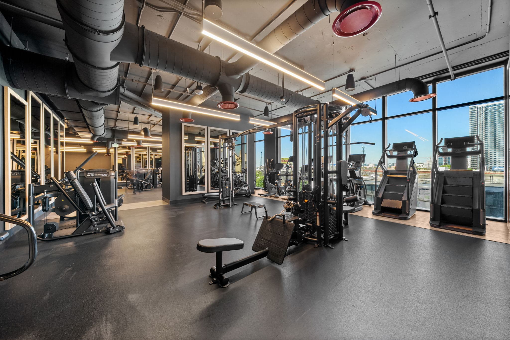 Gym with strength machines and large windows.
