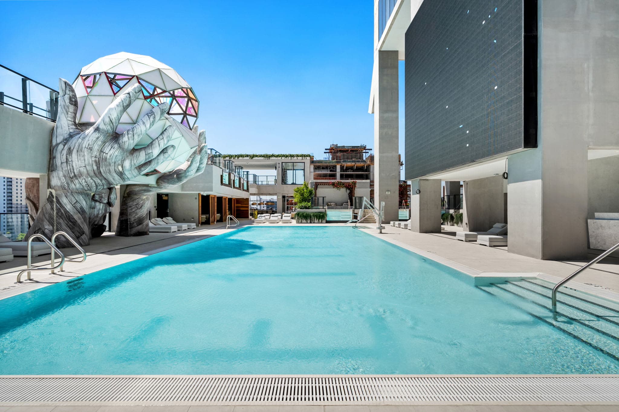 Swimming pool beside a faceted sculpture.