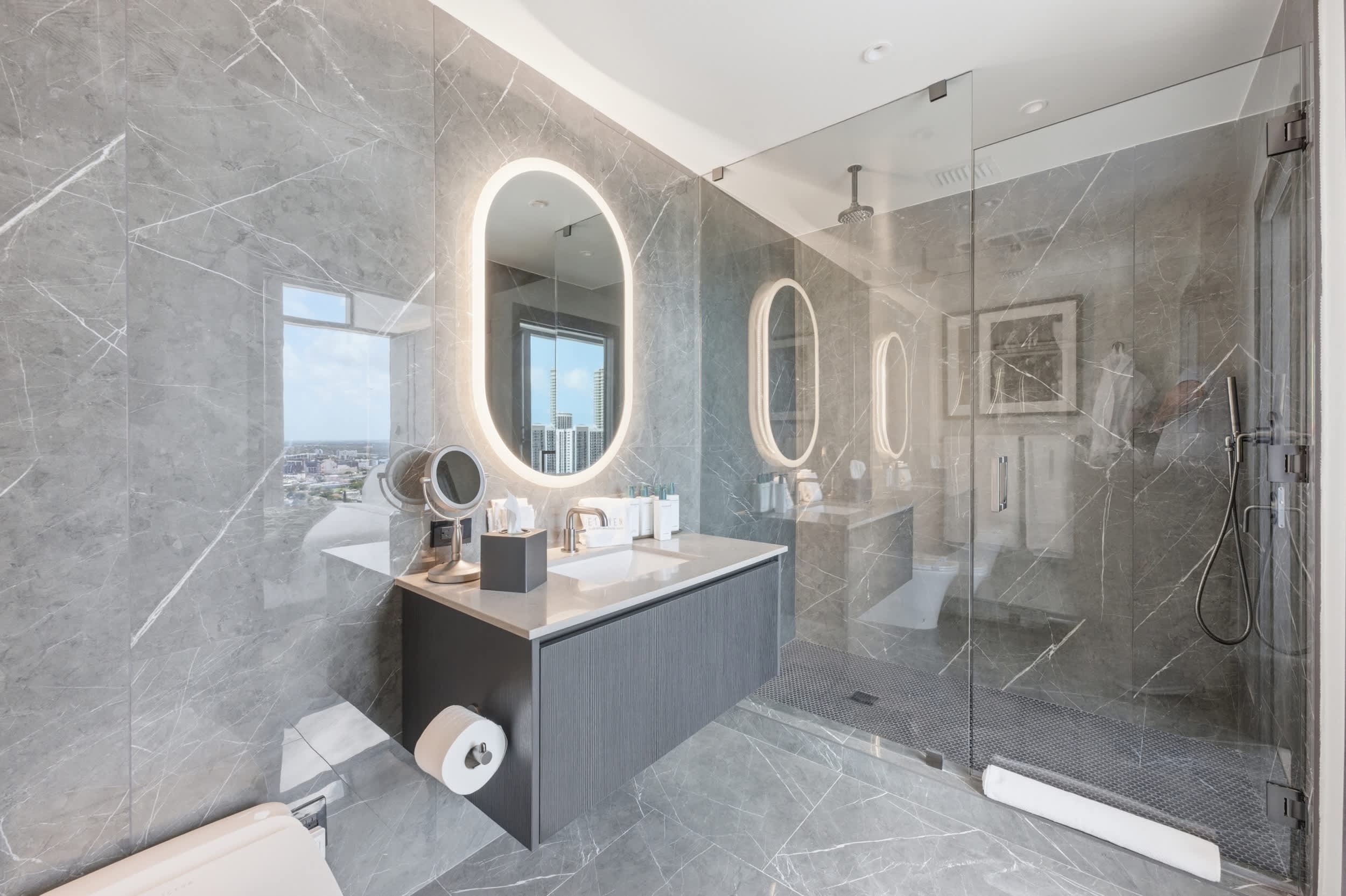 Marble bathroom with an oval mirror and shower.