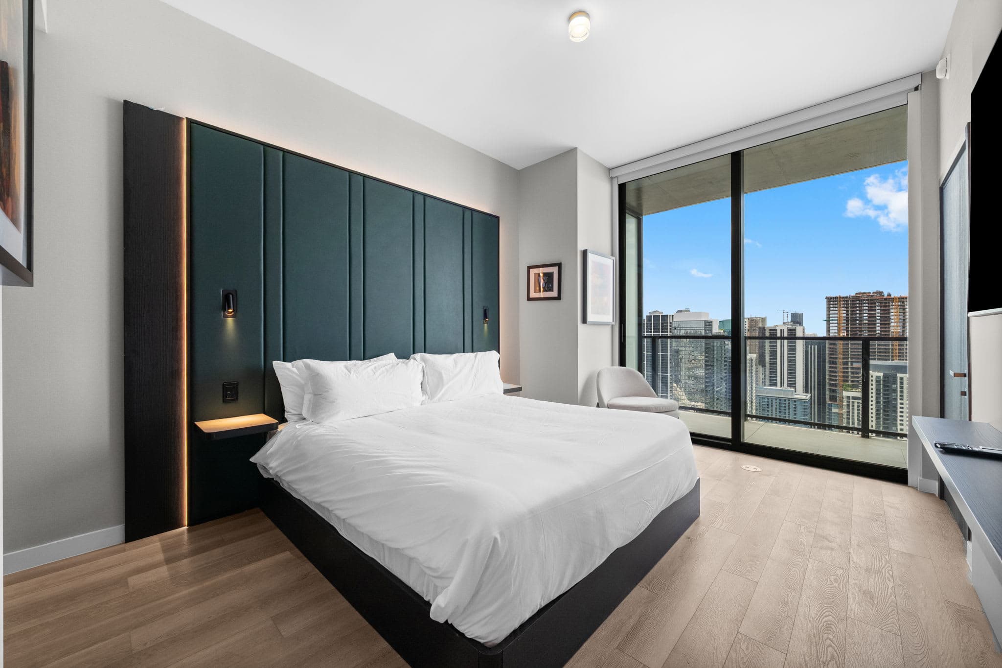 Bed beside large city-view windows.
