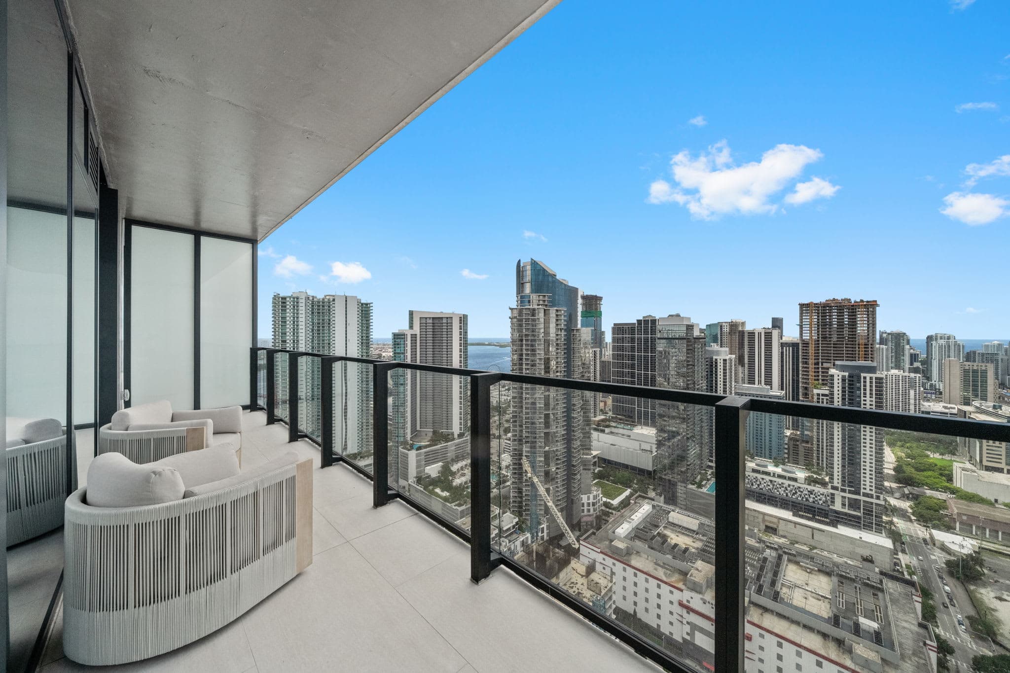 Balcony with woven chairs and city views.