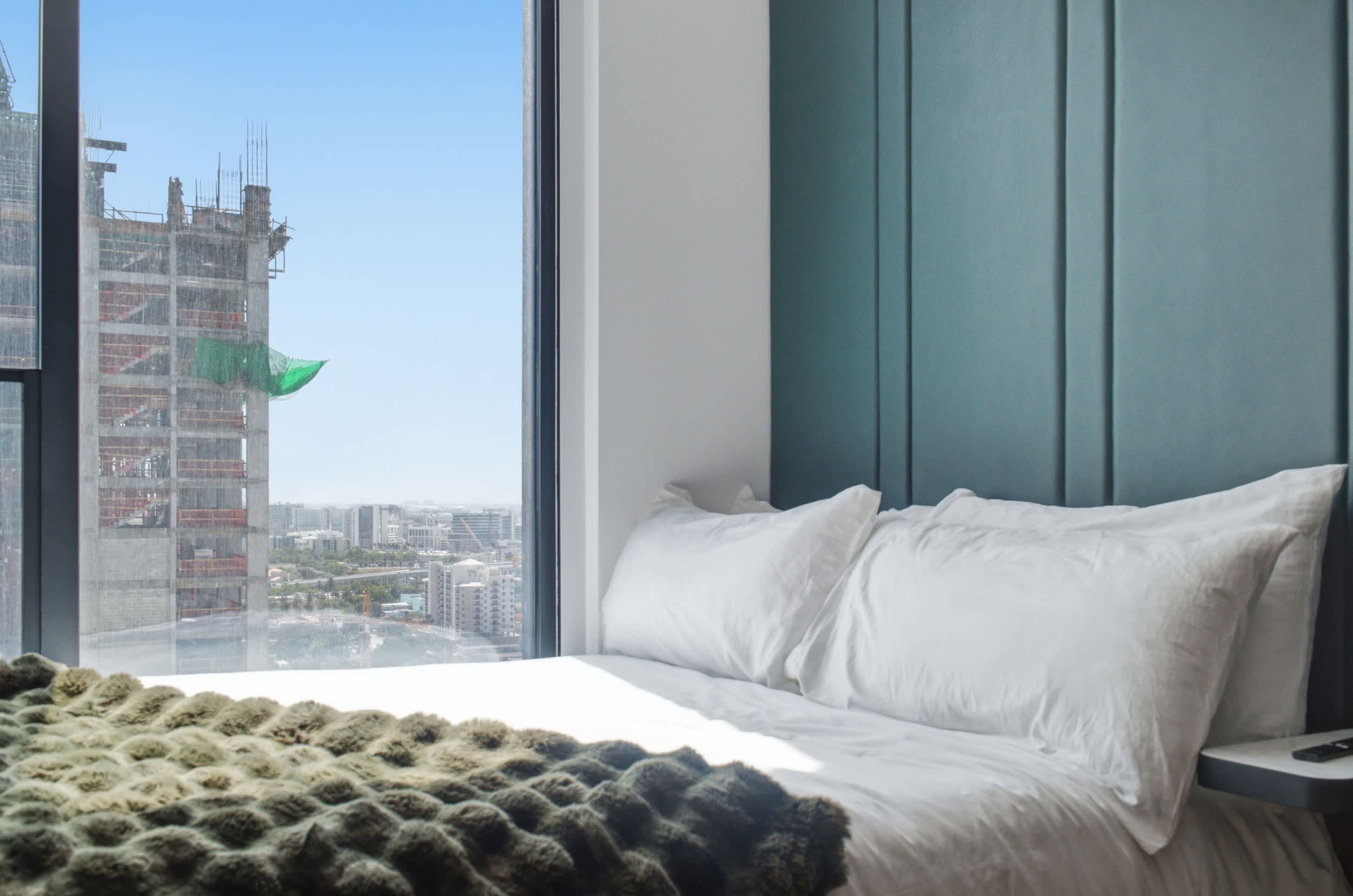 White pillows beside a green headboard and window.
