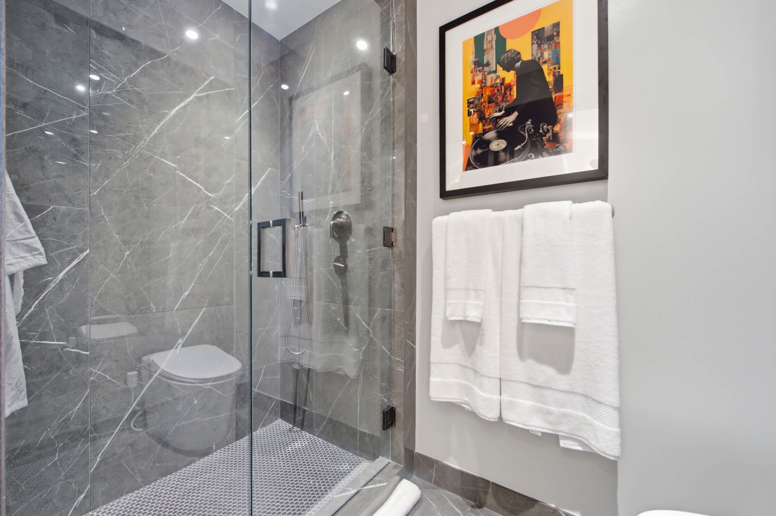 Glass-enclosed shower with marble walls.