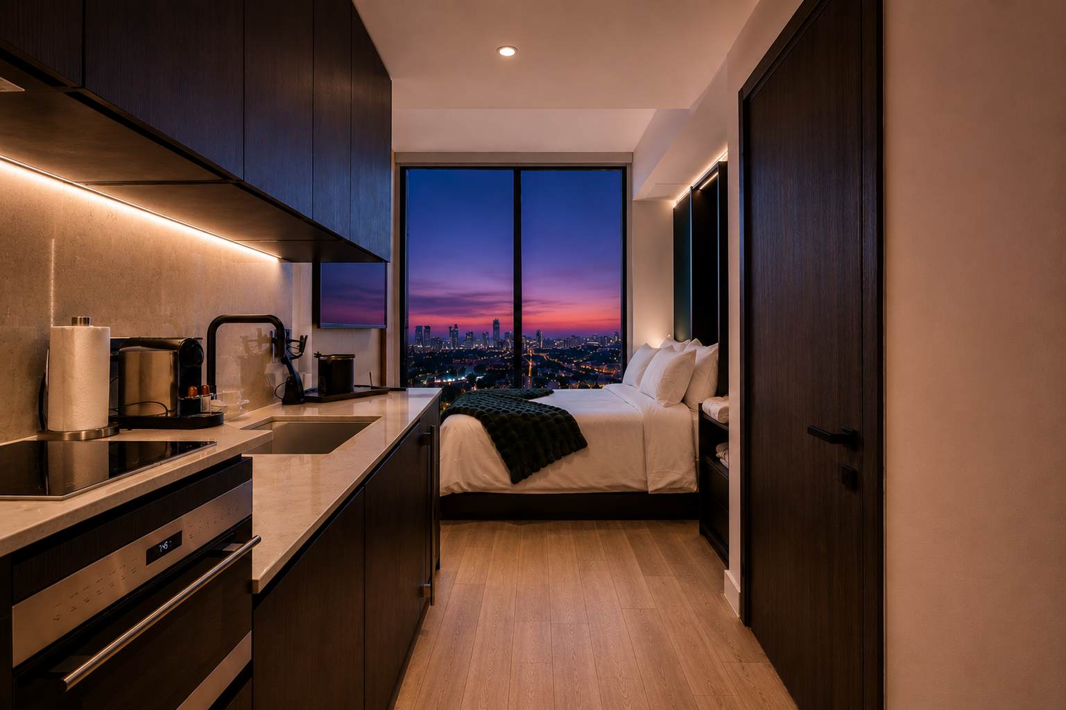 Studio kitchen and bed at dusk.