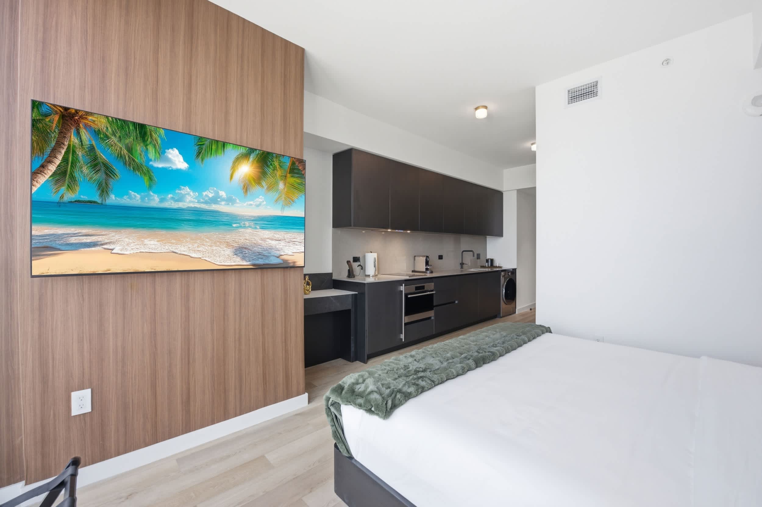 Bed facing a television beside the kitchen.