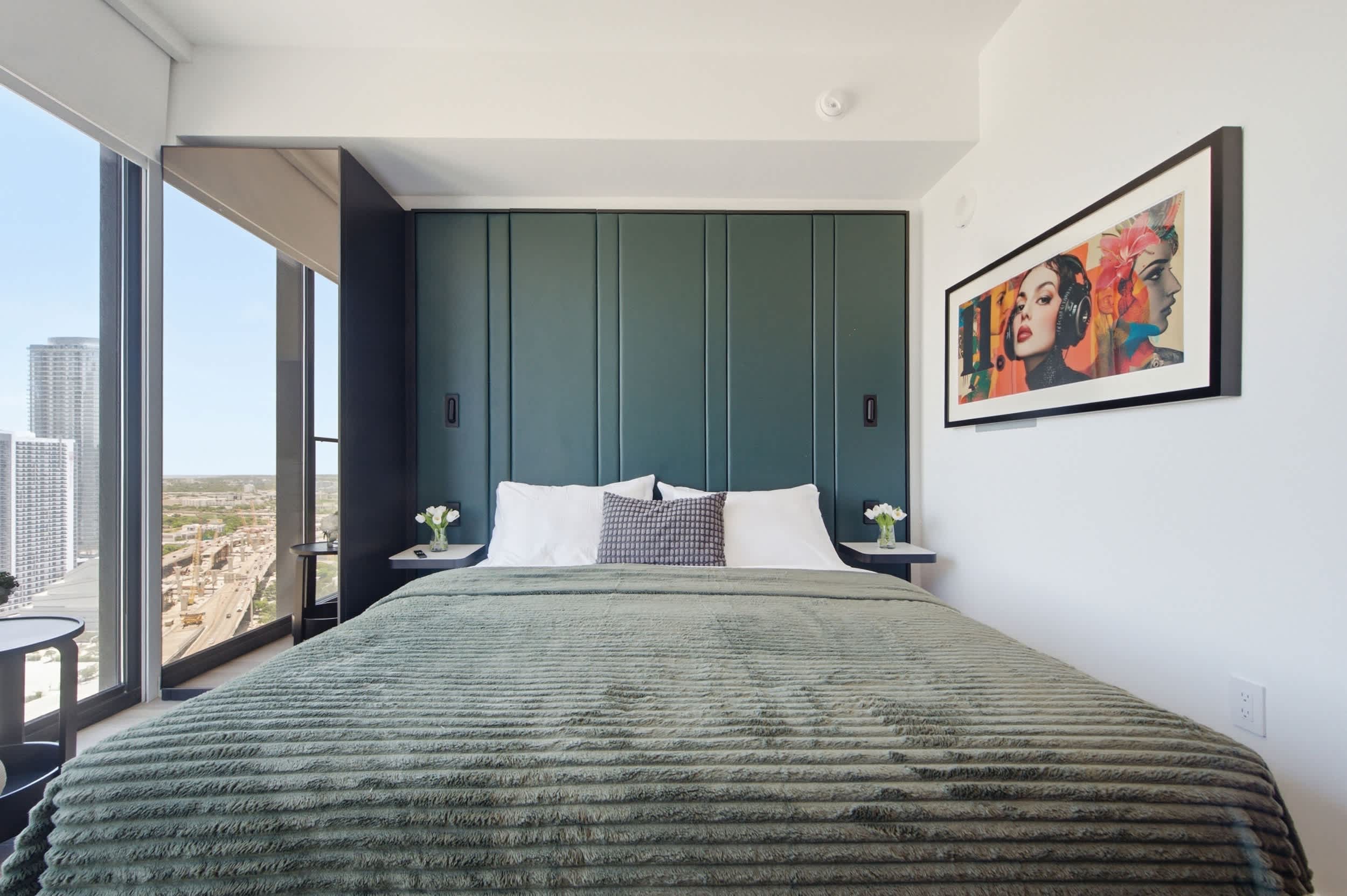 Bed with green bedding and a paneled headboard.