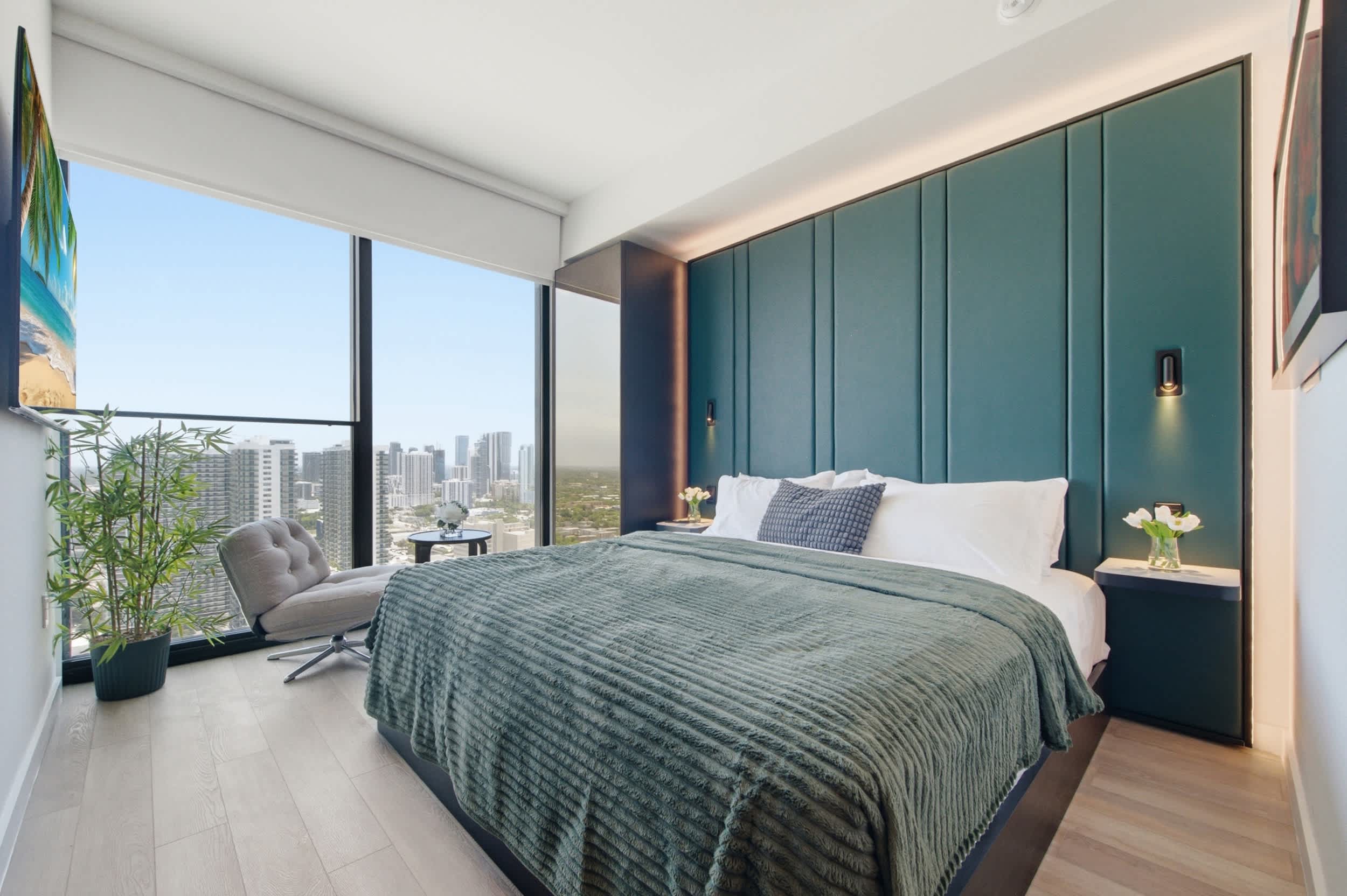 Bedroom with green bedding and tall windows.