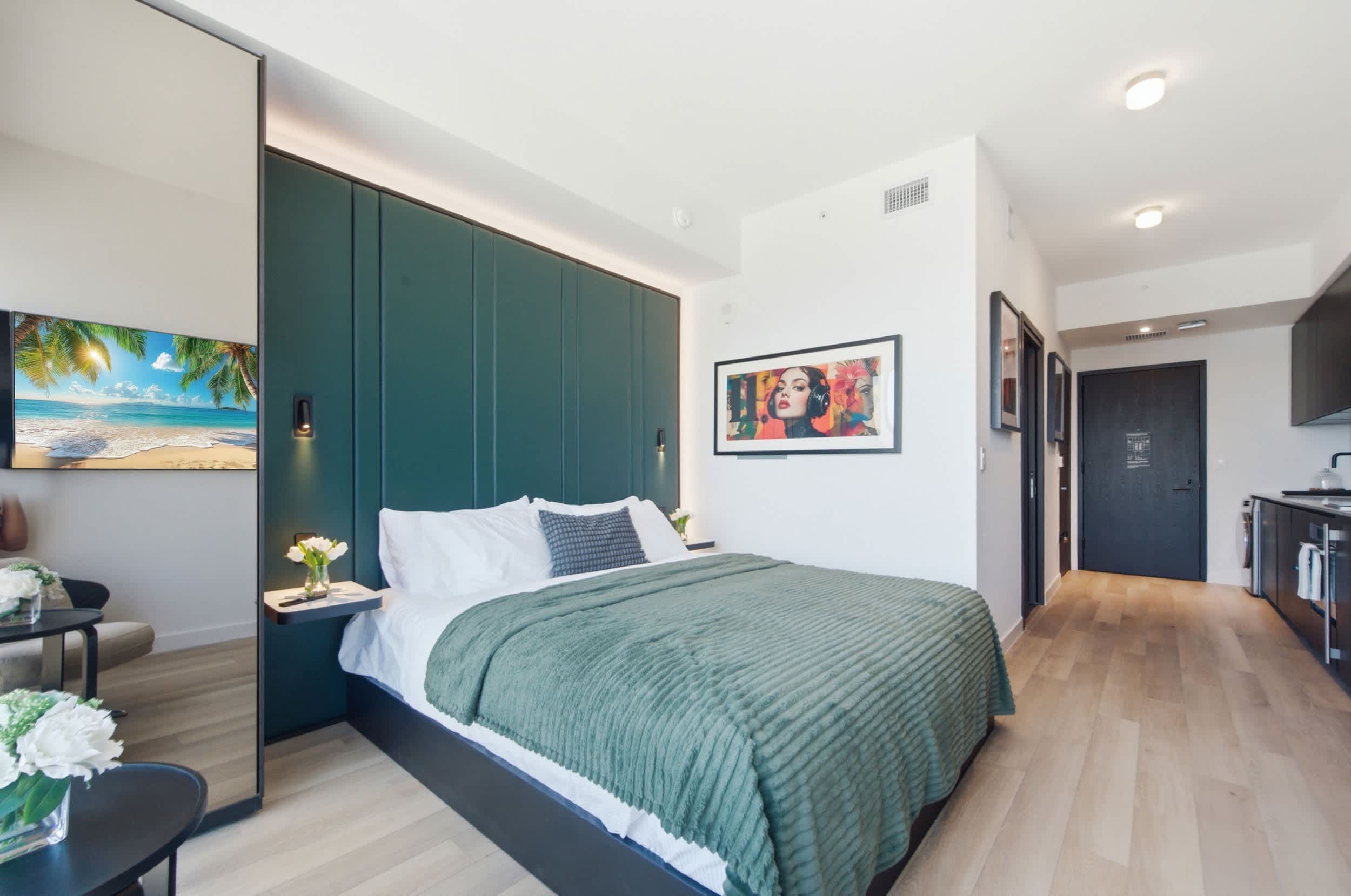 Green-bedded studio with framed wall artwork.