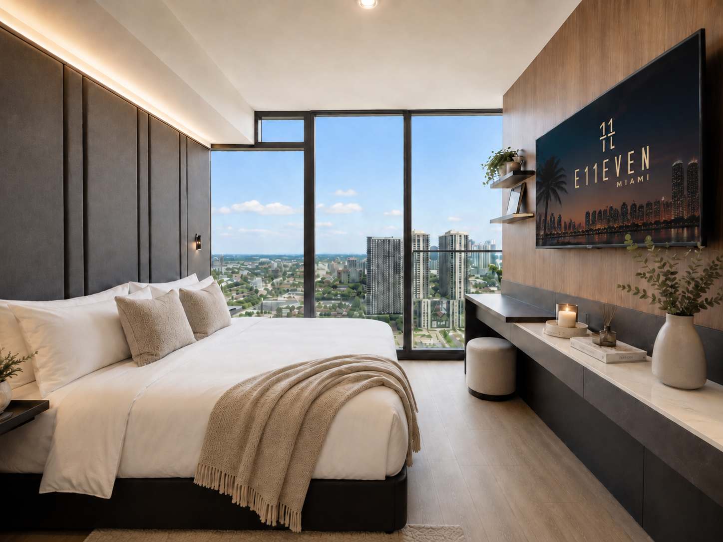 Bed with a beige throw beside city-view windows.