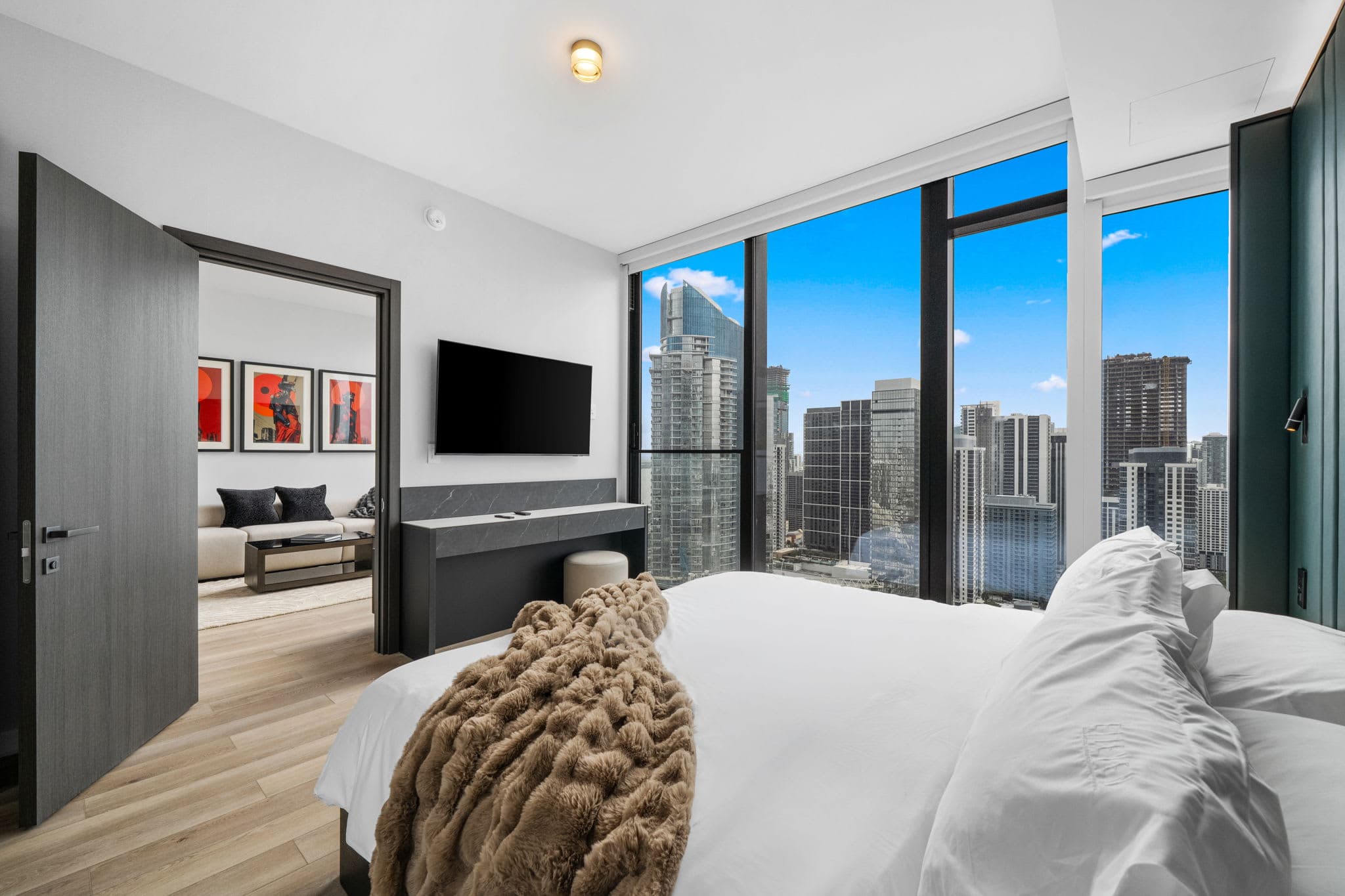 Bed beside large city-view windows.