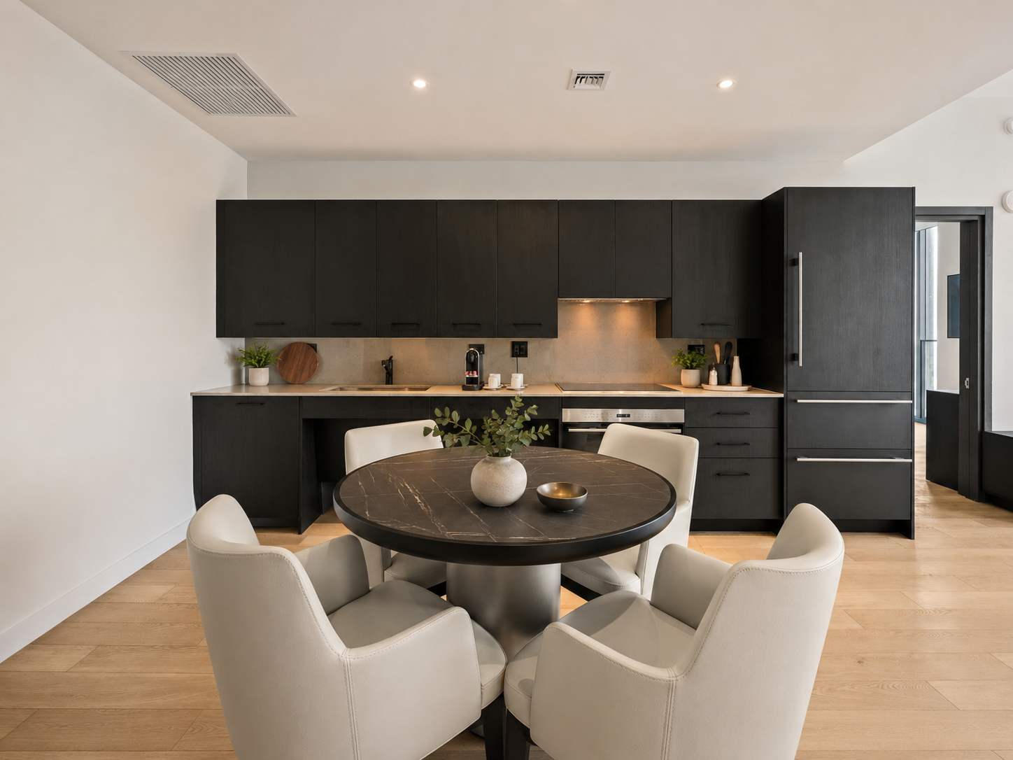 Dining table facing dark kitchen cabinets.