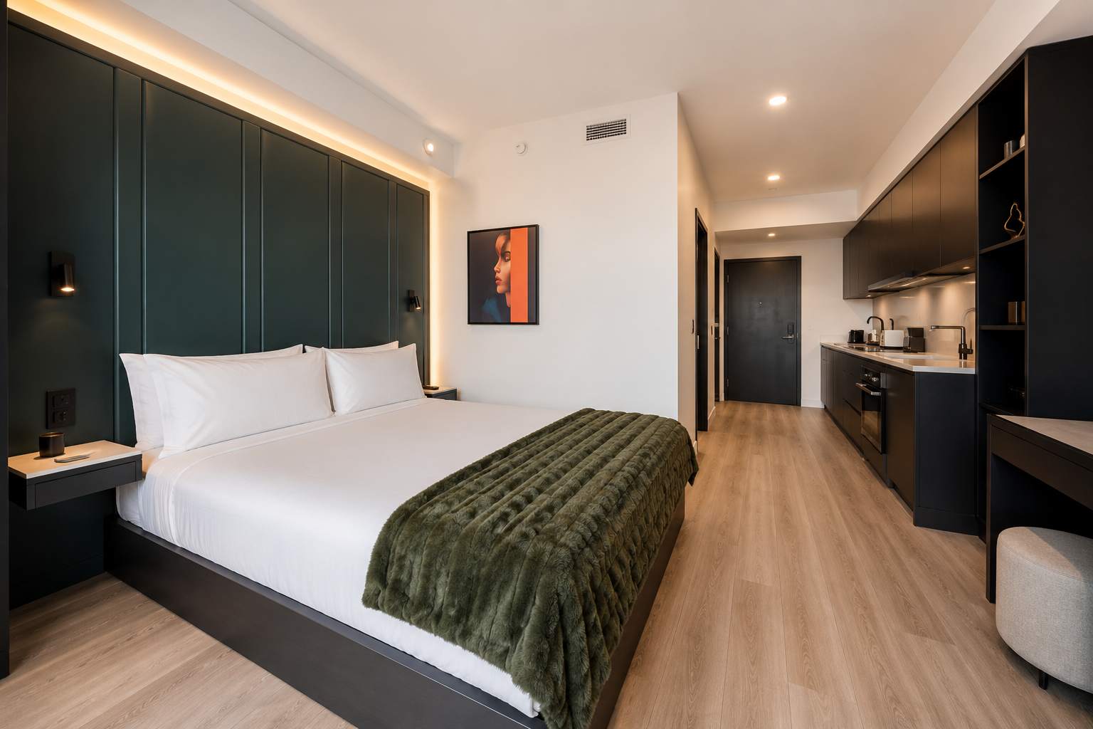 Bed with white linens and a green accent wall.