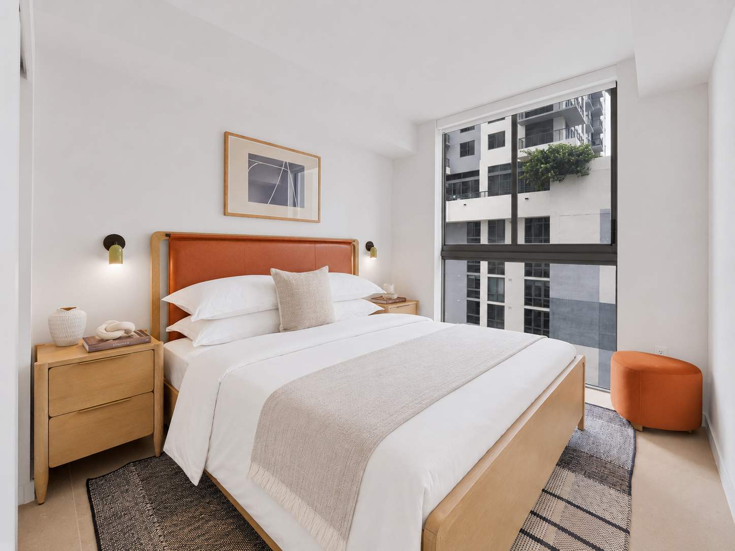 Bed beside large city-view windows.