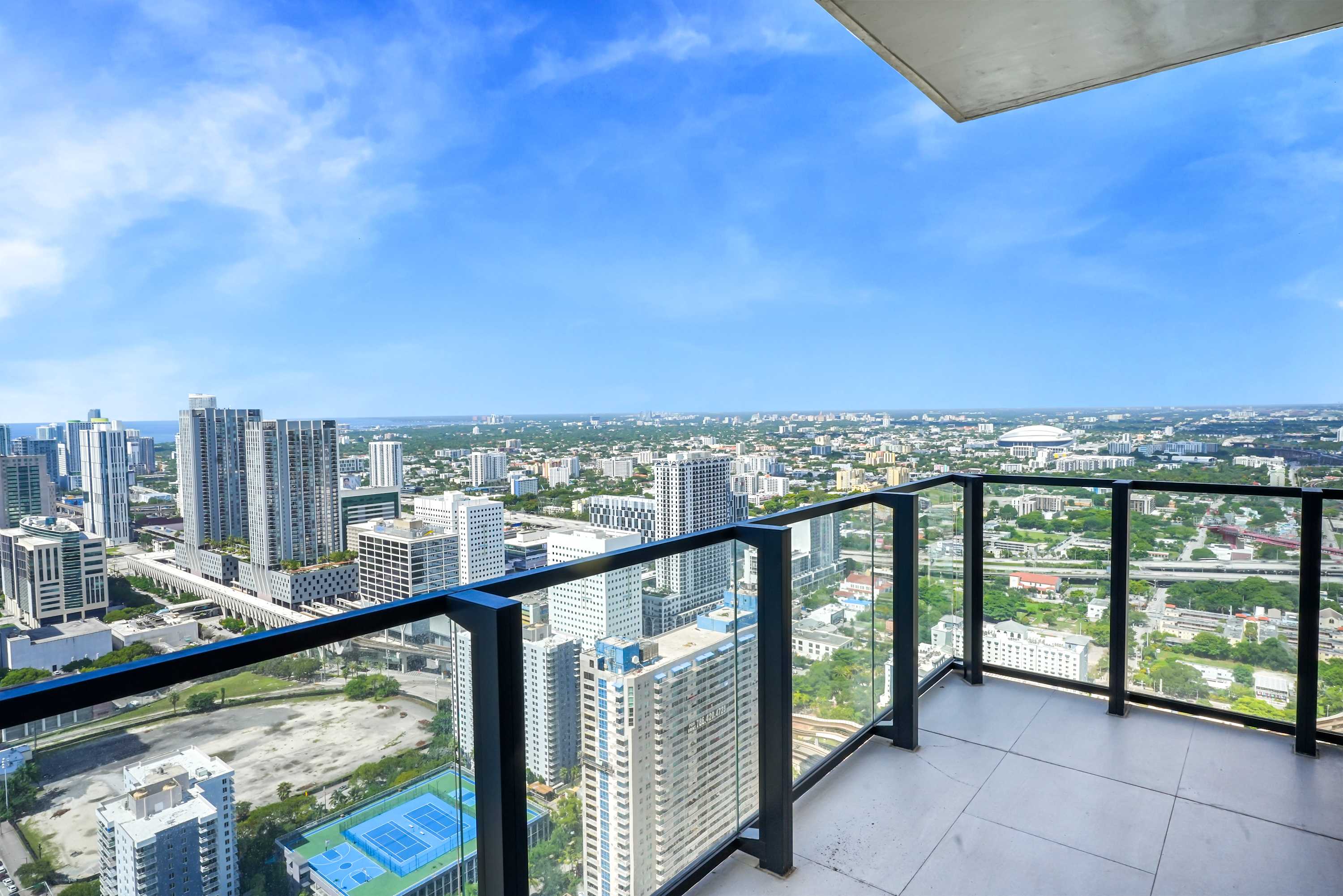 Balcony with glass railings and city views.