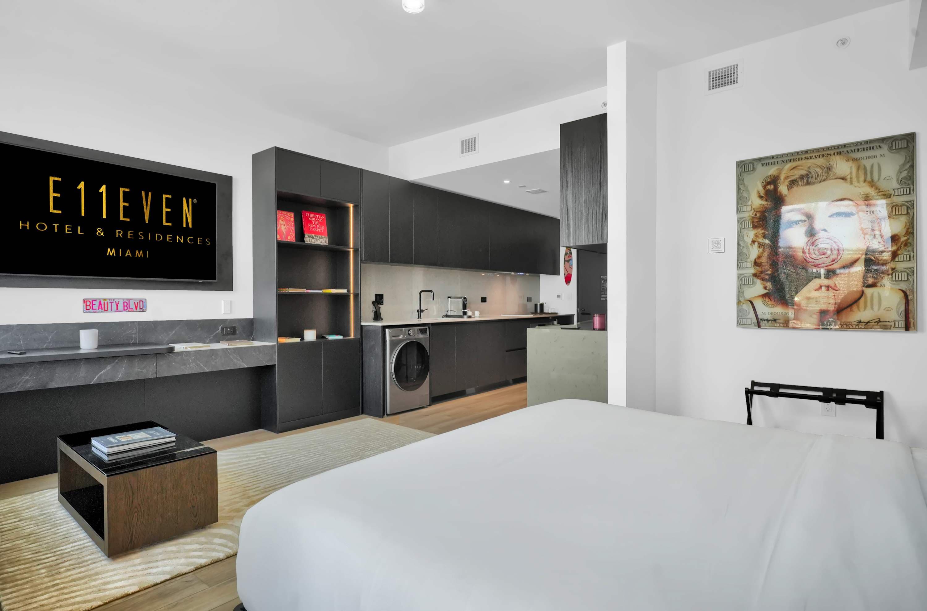 Bed facing a television beside the kitchen.