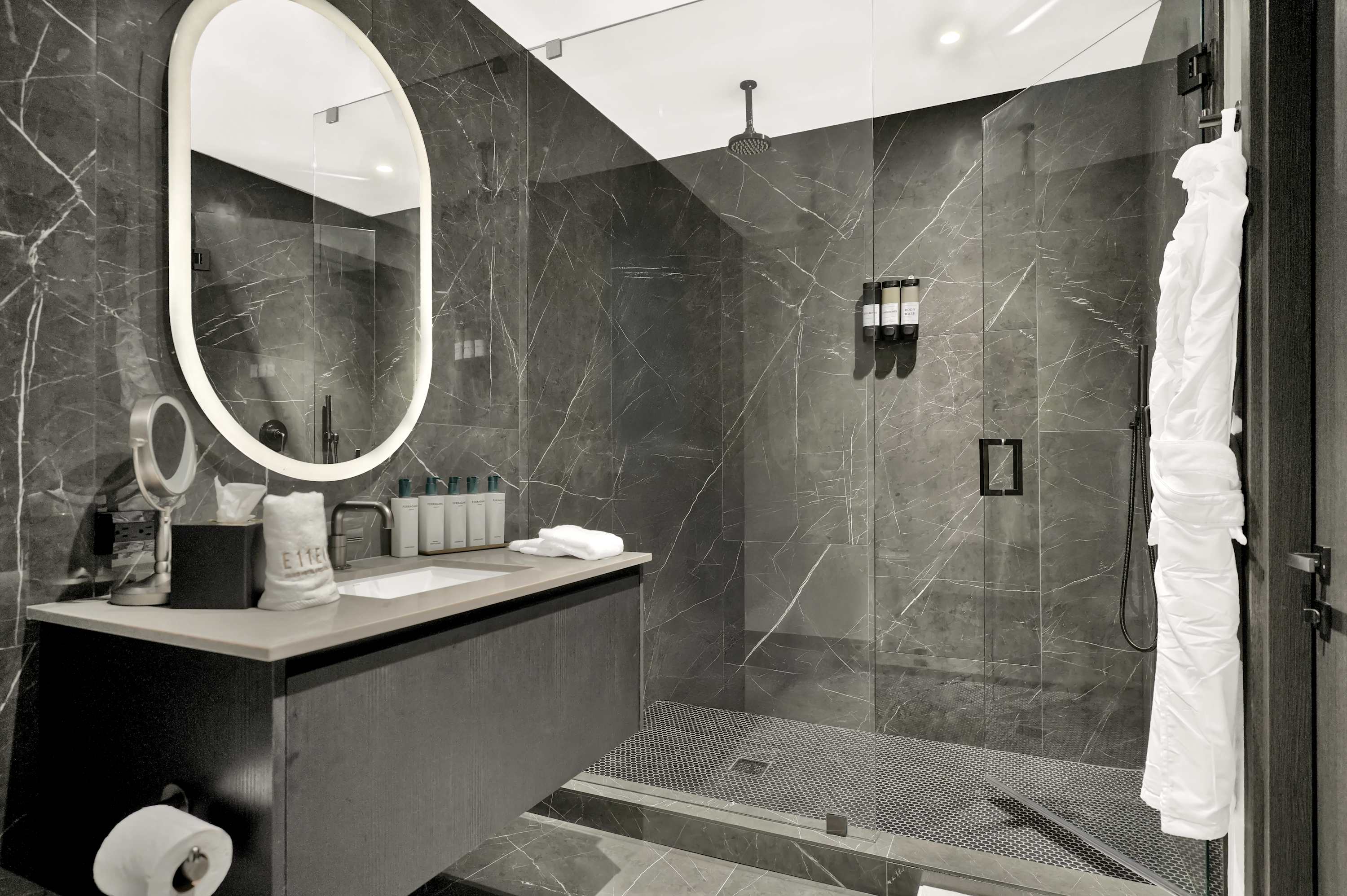 Marble bathroom with an oval mirror and shower.
